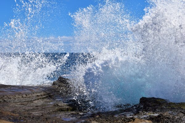 A wave crashing on the rocks of the beach.