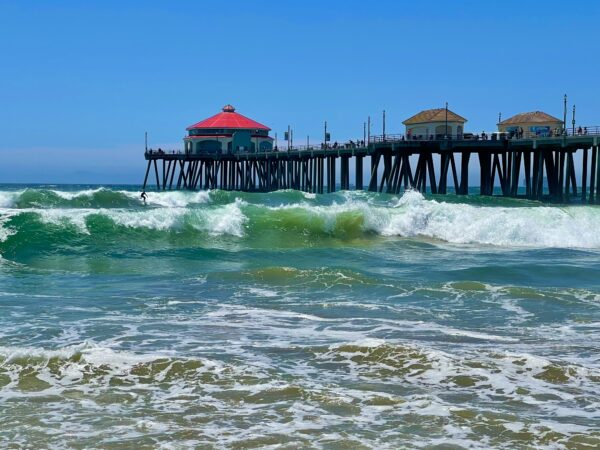 A pier with waves crashing on it and the ocean in front of it.