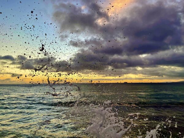 A view of the ocean with birds flying in it.