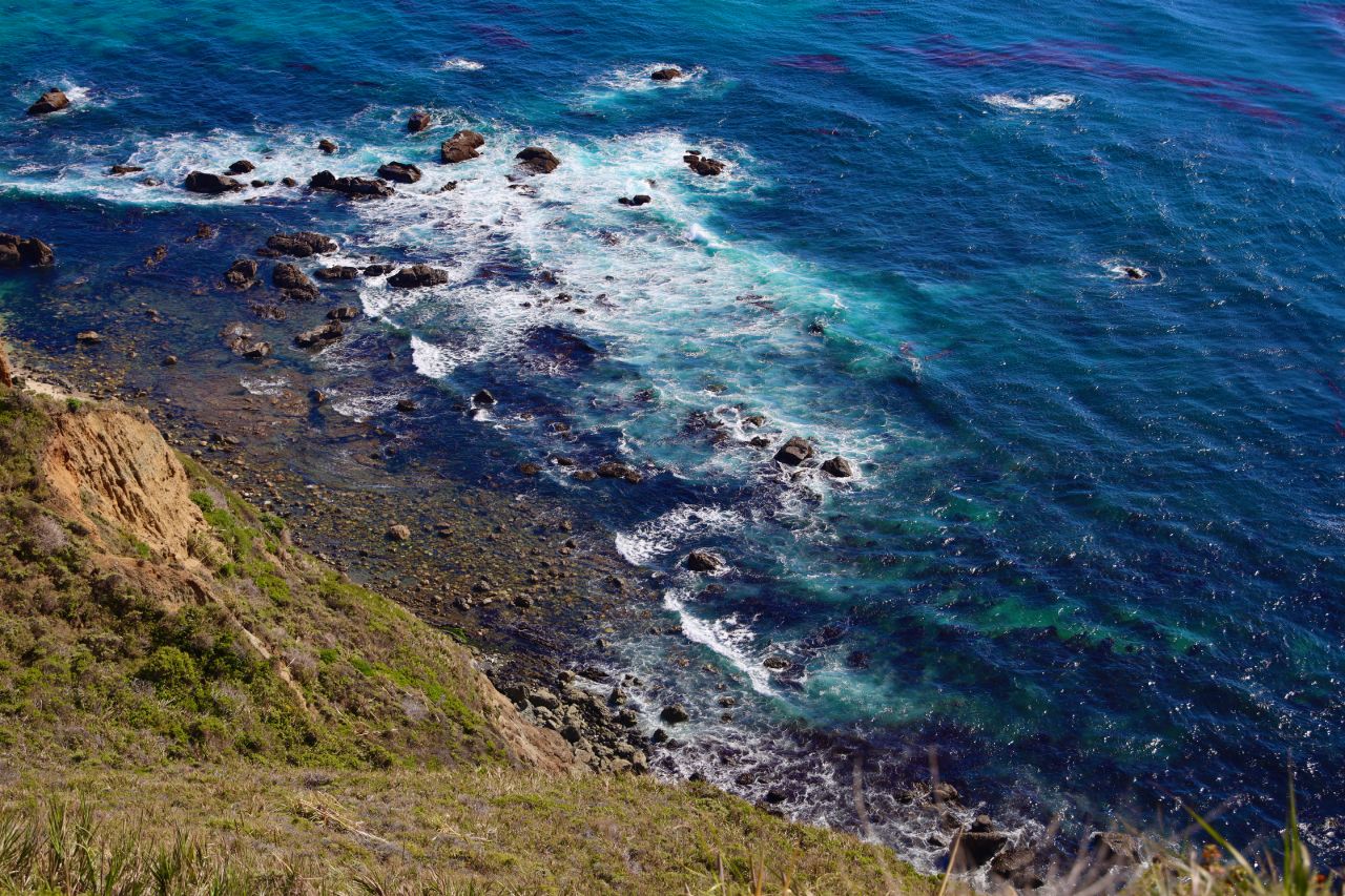 A view of the blue ocean and rocks from a cliff