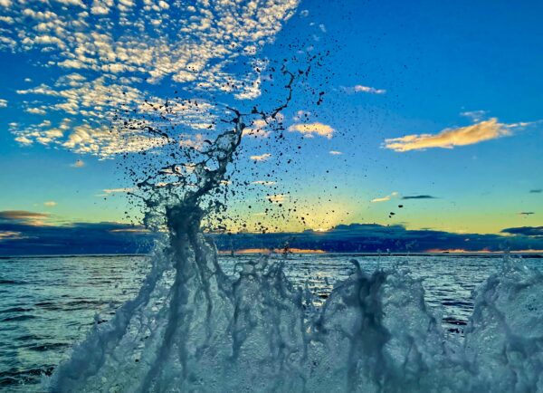 A water splash in the ocean with clouds above.