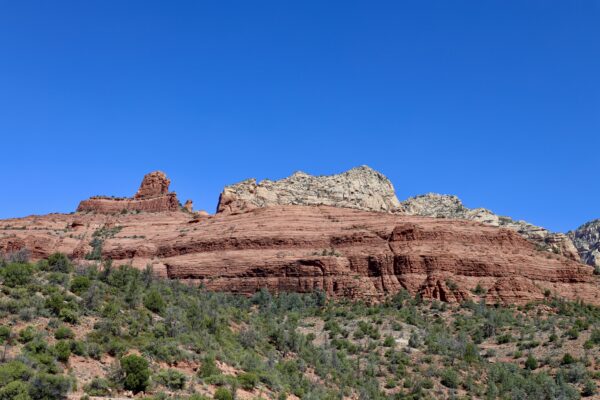 A mountain with red rocks and trees in the foreground.