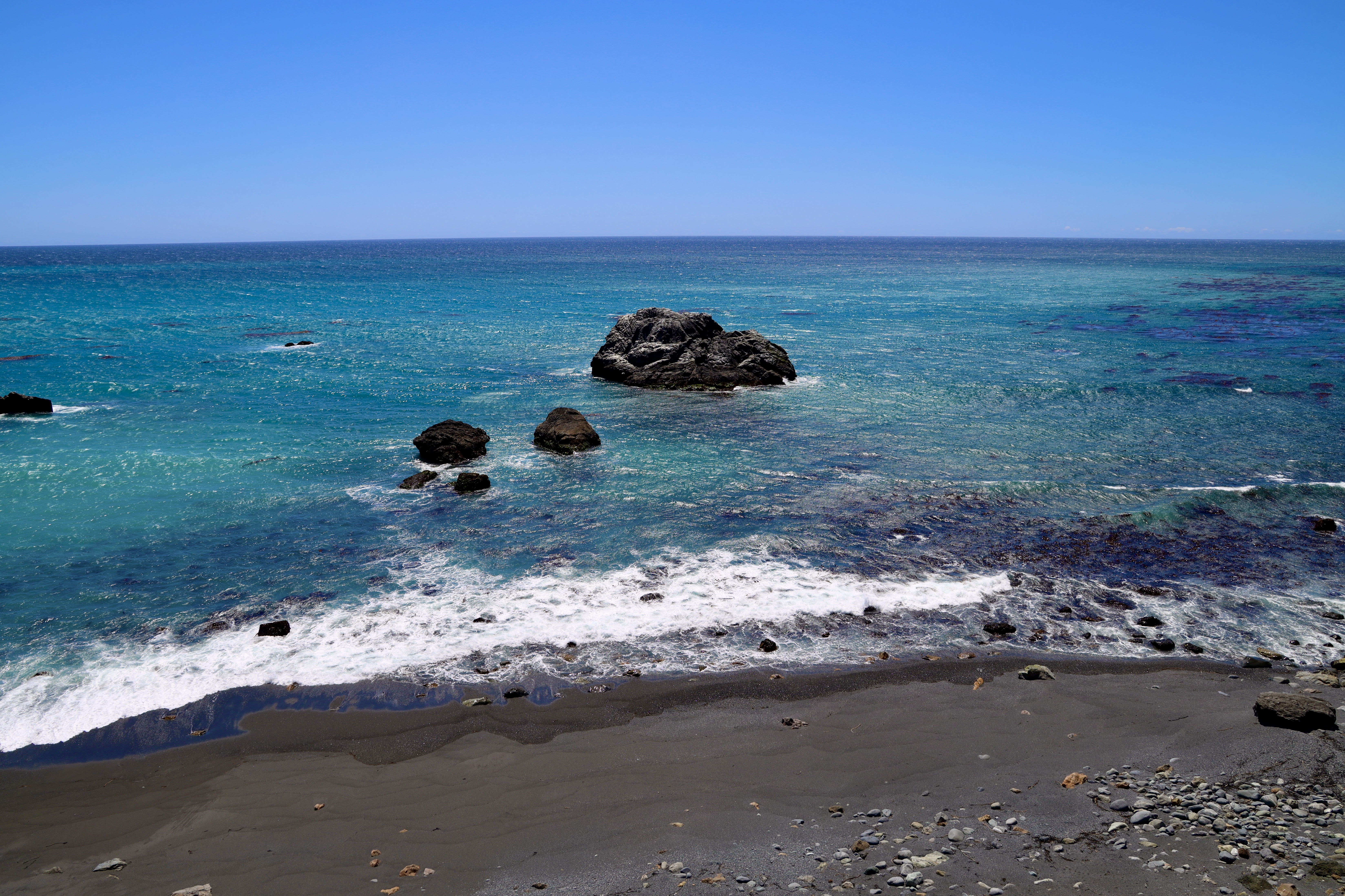 A beach with rocks and water in the ocean.