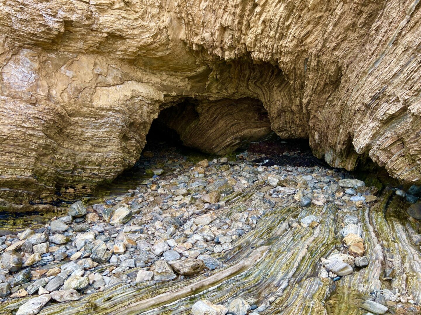 A rock cave with rocks and grass in the foreground.